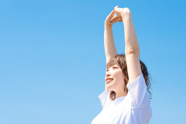 手を組んで上に伸ばす女性