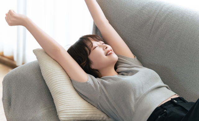 ソファで伸びをする女性