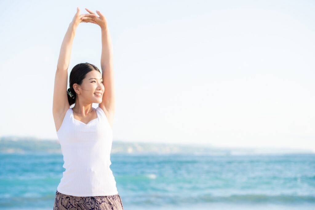 海辺で伸びをする女性